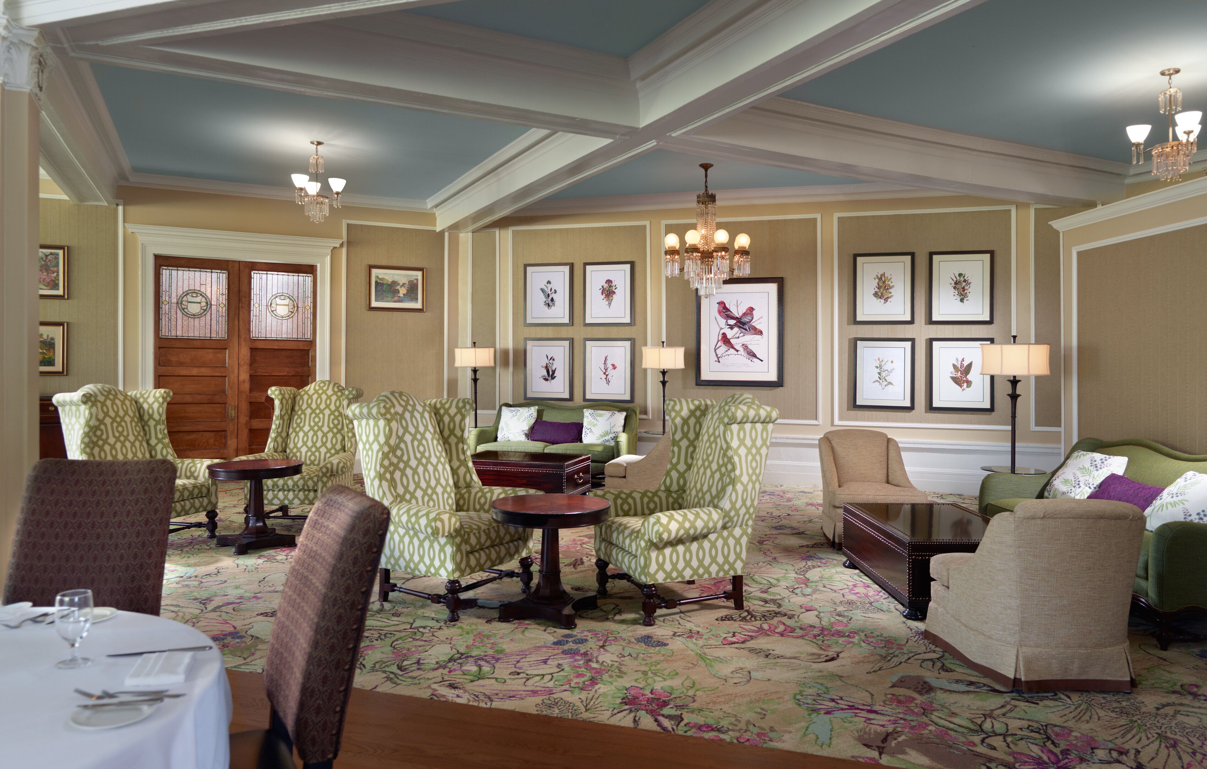 A spacious room with a dining area, multiple seating arrangements, and a chandelier.