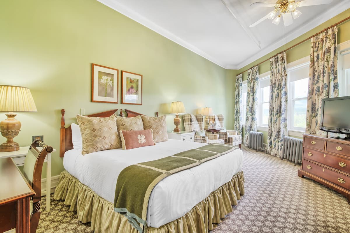 A well-appointed bedroom with a large bed, a television, a desk, and a chair.