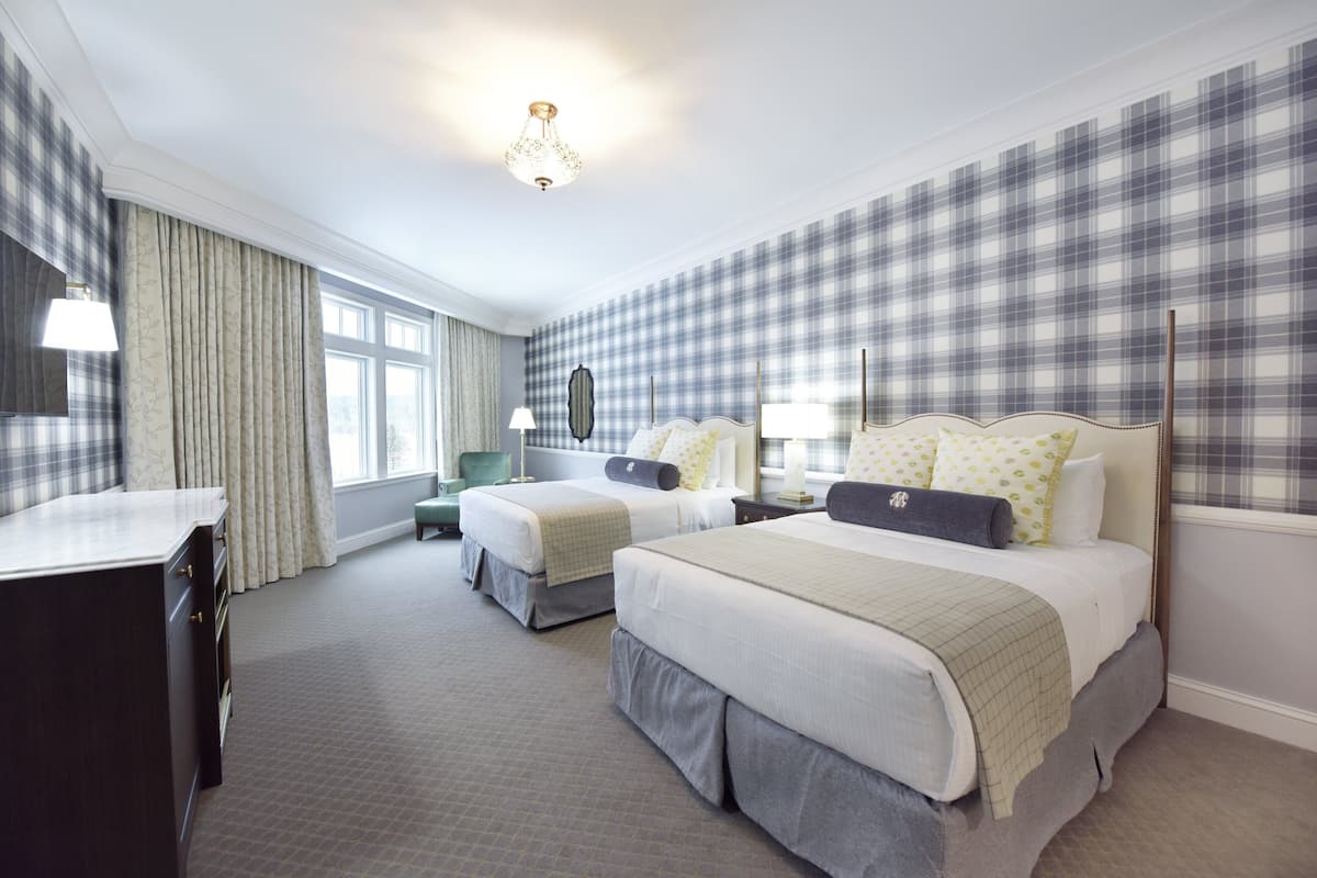 Een hotelkamer met twee bedden, een bureau en een stoel.