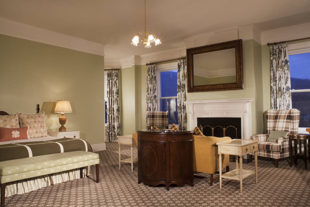 A traditional room with a fireplace, a large mirror, and a plaid armchair.