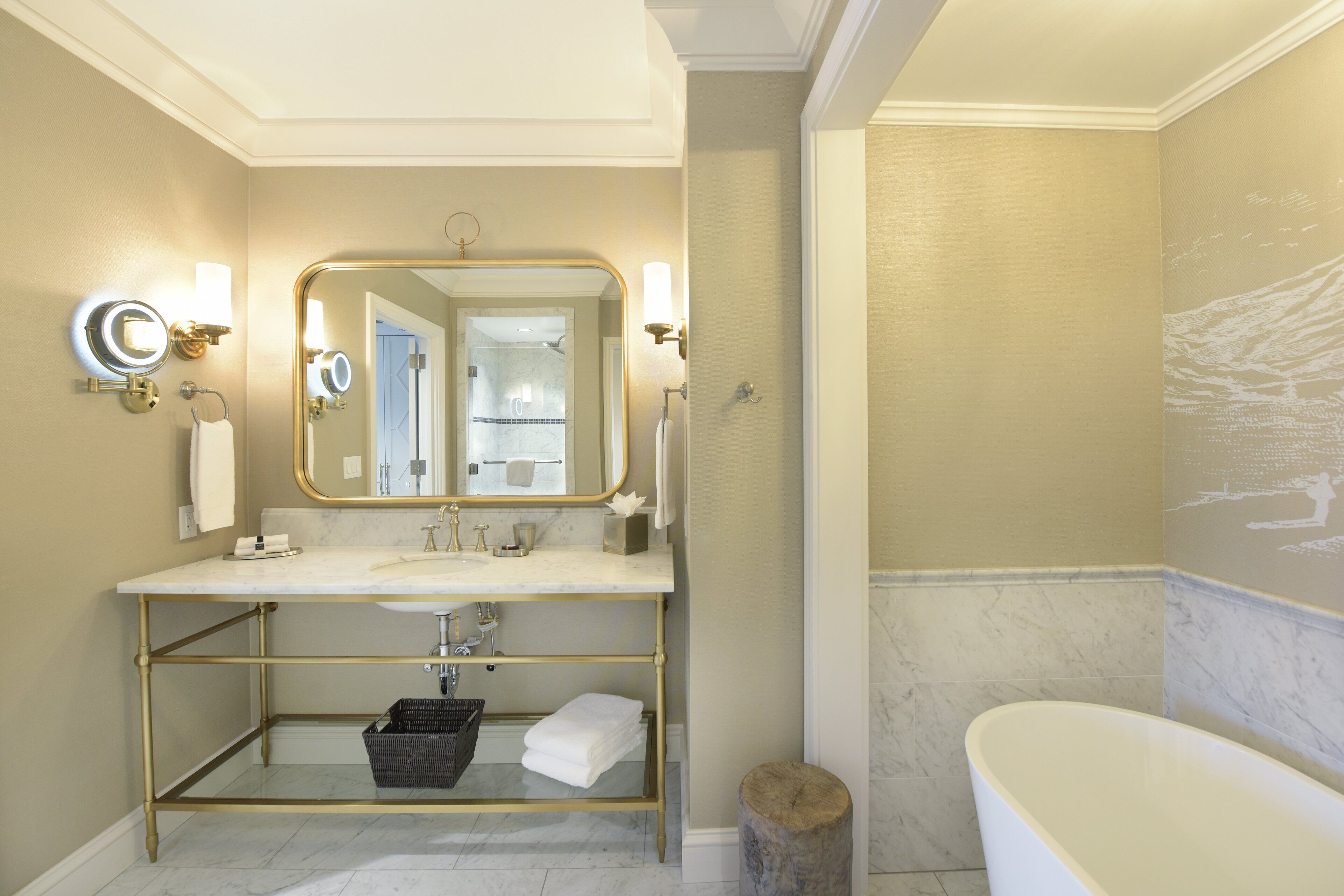 A bathroom with a gold-framed vanity, a large mirror, and a bathtub.
