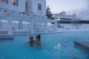 Une piscine avec un belvédère blanc et un paysage enneigé en arrière-plan.