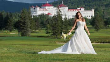 A wedding dress on a grassy field with a building in the background.