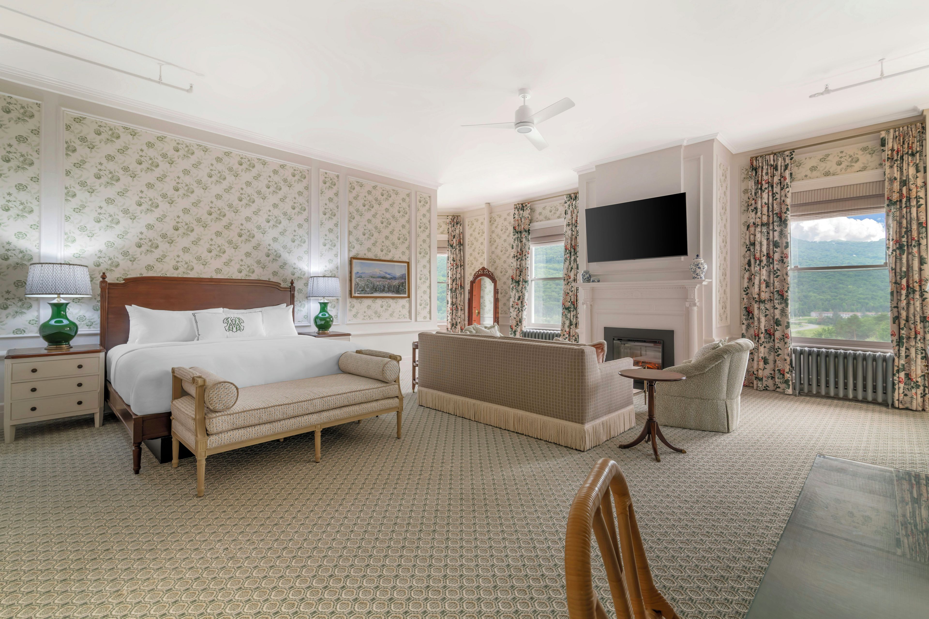 Une chambre d’hôtel comprenant un lit, un canapé, un fauteuil, une cheminée, un téléviseur et une vue sur l’extérieur.
