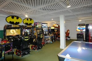 A room with multiple arcade machines, including Batman-themed ones, and a foosball table.