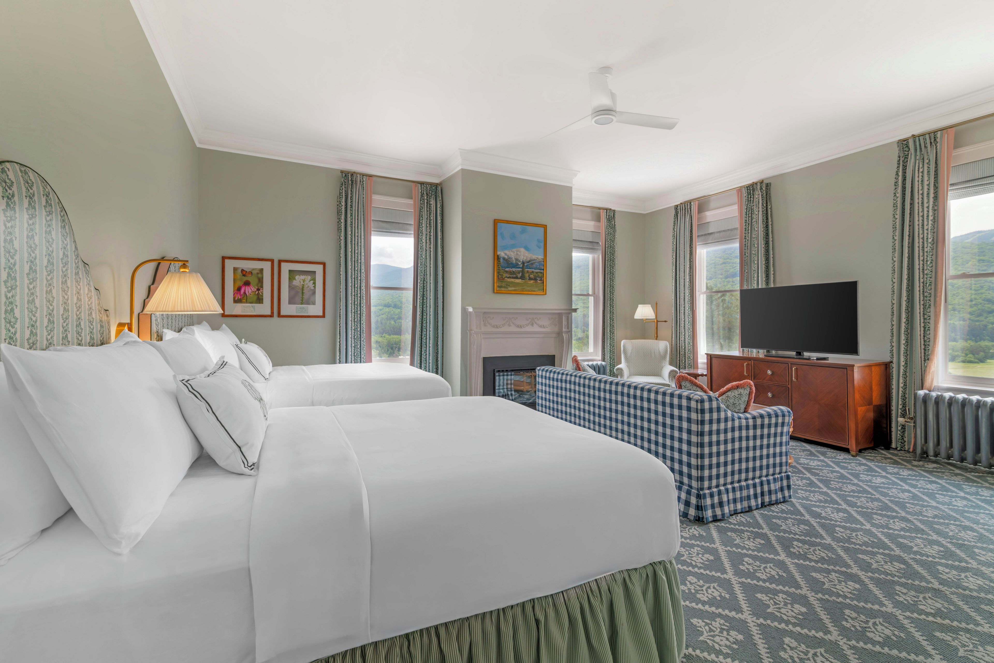 A hotel room with a bed, a sofa, a television, and a fireplace.