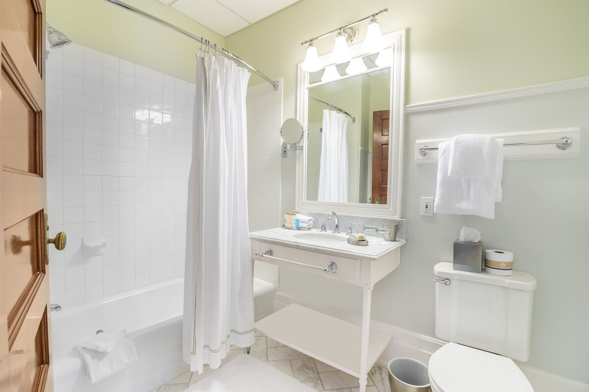 Een badkamer met een bad, een wastafel, een spiegel en een toilet.