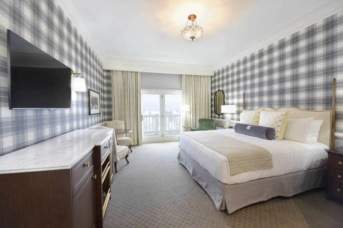 Een hotelkamer met een groot bed, een flatscreen televisie, een bureau en een stoel.
