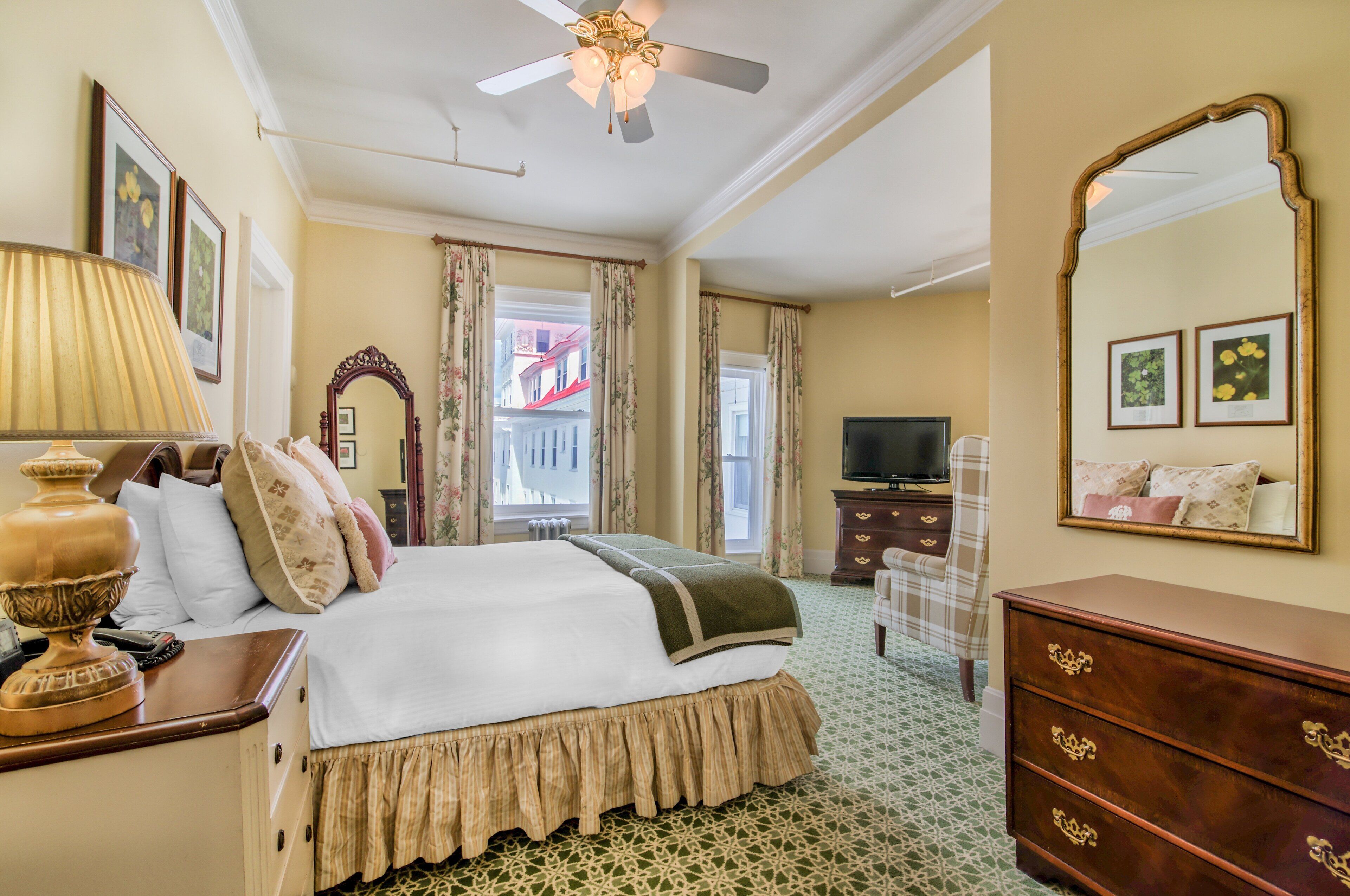 Une chambre d’hôtel avec un lit, une commode, un miroir et un téléviseur.