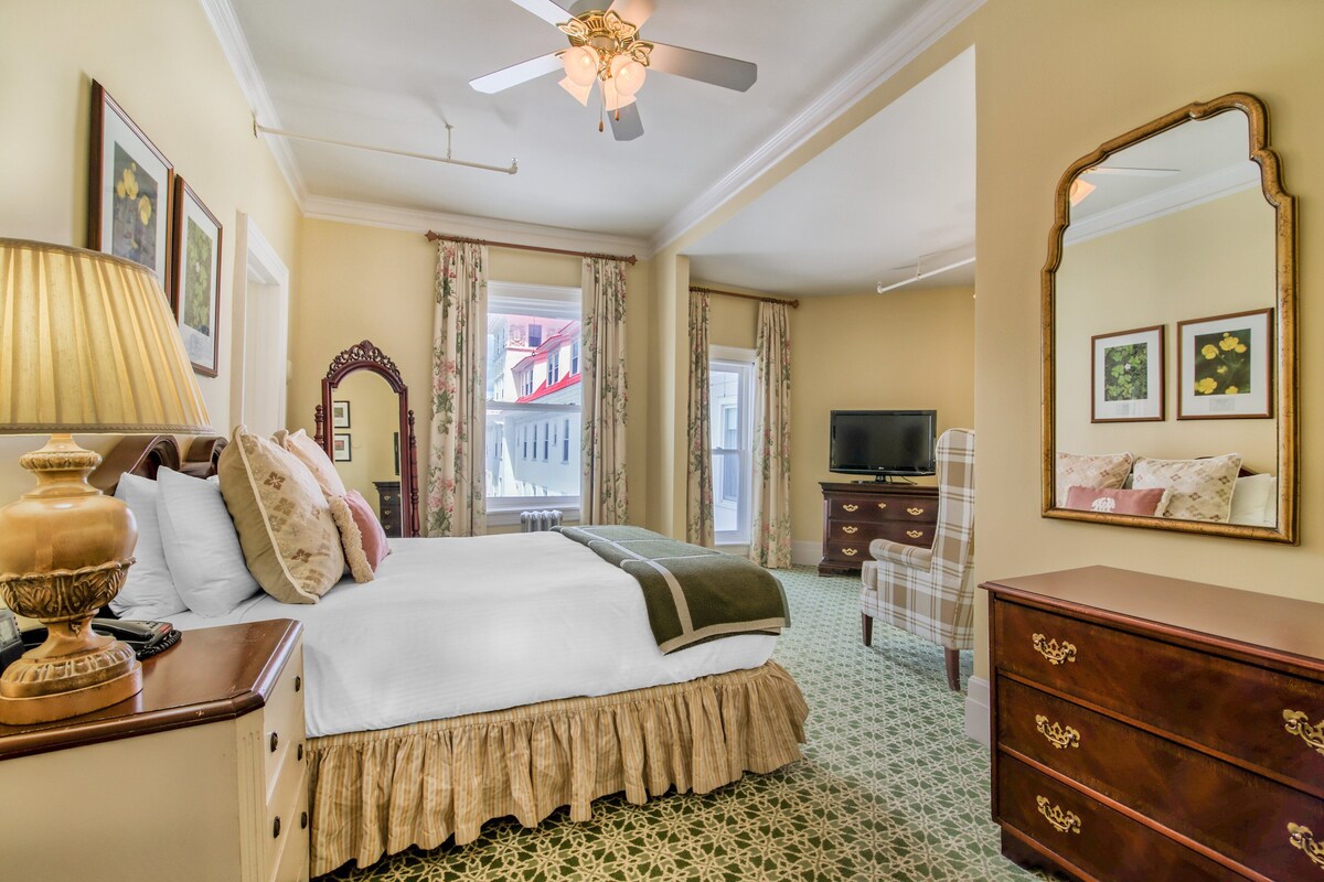 Une chambre d’hôtel avec un lit, une commode, un miroir et un téléviseur.