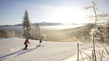 A snowy ski slope with a person skiing.