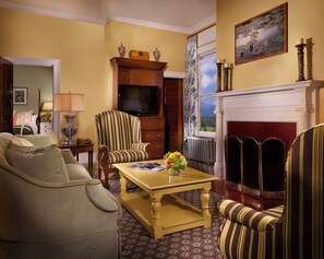 A traditional living room with a sofa, armchairs, a coffee table, a television, and a fireplace.