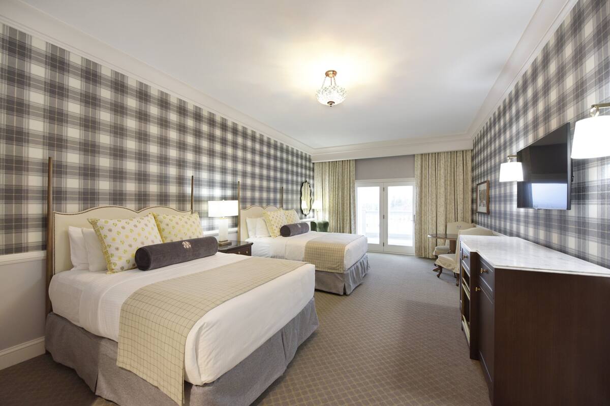 Een hotelkamer met twee bedden, een dressoir, een spiegel en een televisie.