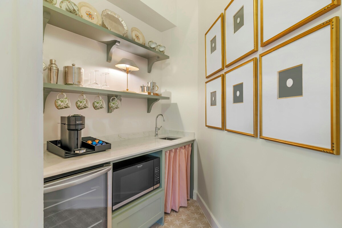 Een compacte keuken met een ingebouwde espressomachine, een spoelbak en een afdruiprek.