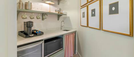 A compact kitchen with a built-in espresso machine, a sink, and a dish rack.