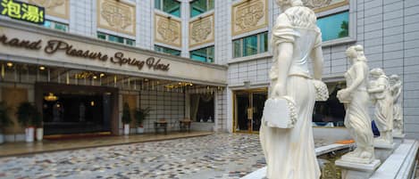 A hotel entrance with a tiled floor and a statue of a woman holding a basket.