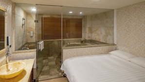 A hotel room with a glass-enclosed shower, a large sink, and a bed with white bedding. - Grand Pleasure Spring Hotel (Taipei)