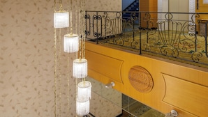 A multi-level interior with ornate metal railings, a patterned wall, and a chandelier. - Grand Pleasure Spring Hotel (Taipei)
