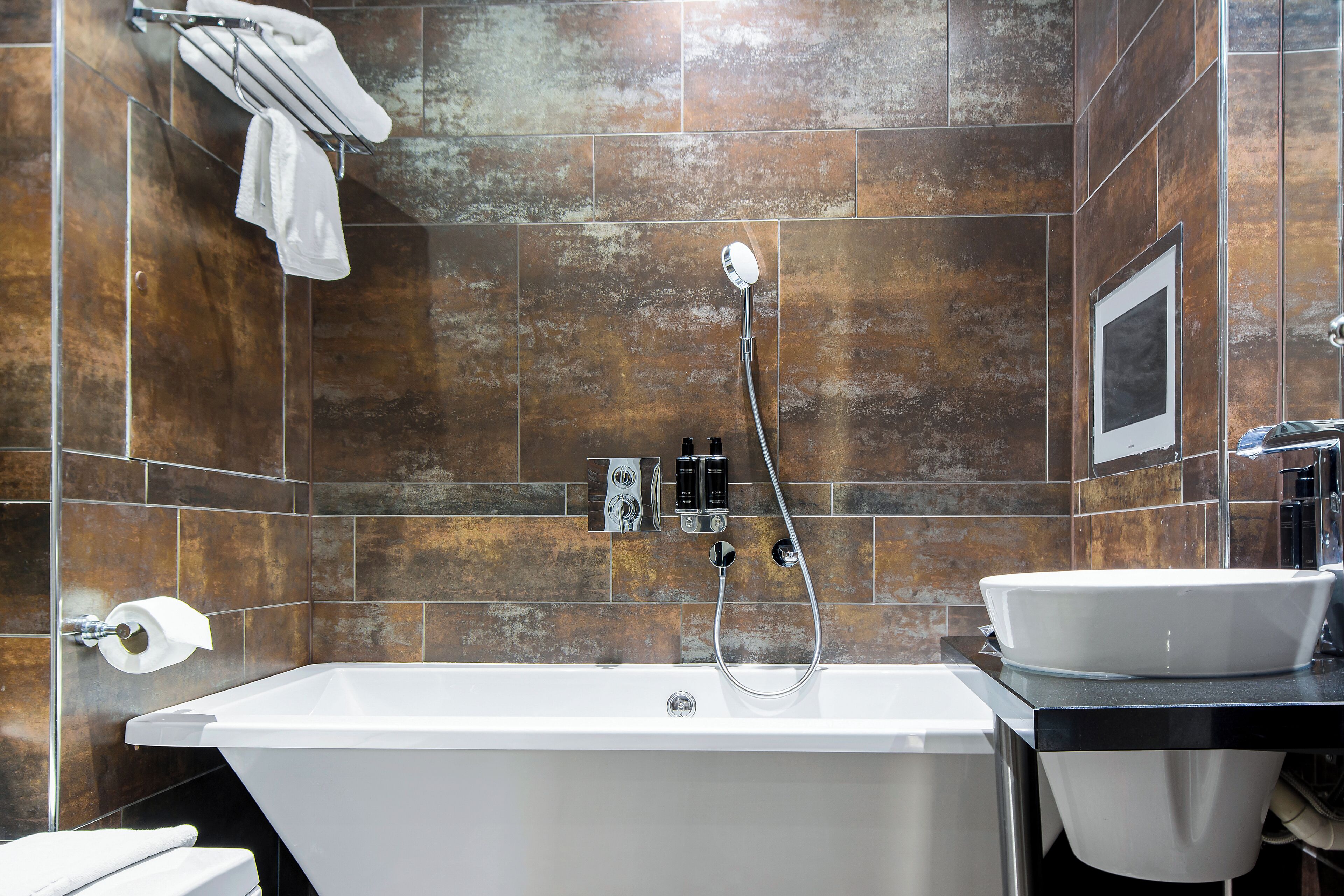 Un baño moderno con una bañera independiente, un perchero de pared y un lavamanos empotrado.