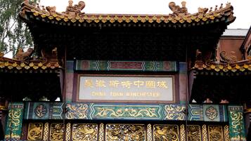 A traditional Chinese architectural structure with ornate decorations and a sign reading "China Town Manchester".