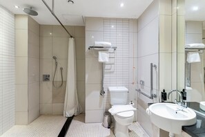 A modern bathroom with a shower, toilet, and sink. - Roomzzz Manchester City (Manchester)