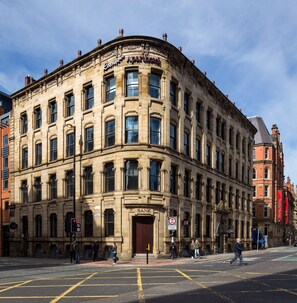 A historic building with a corner entrance, large windows, and a prominent 'Bank' sign. - Roomzzz Manchester City (Manchester)