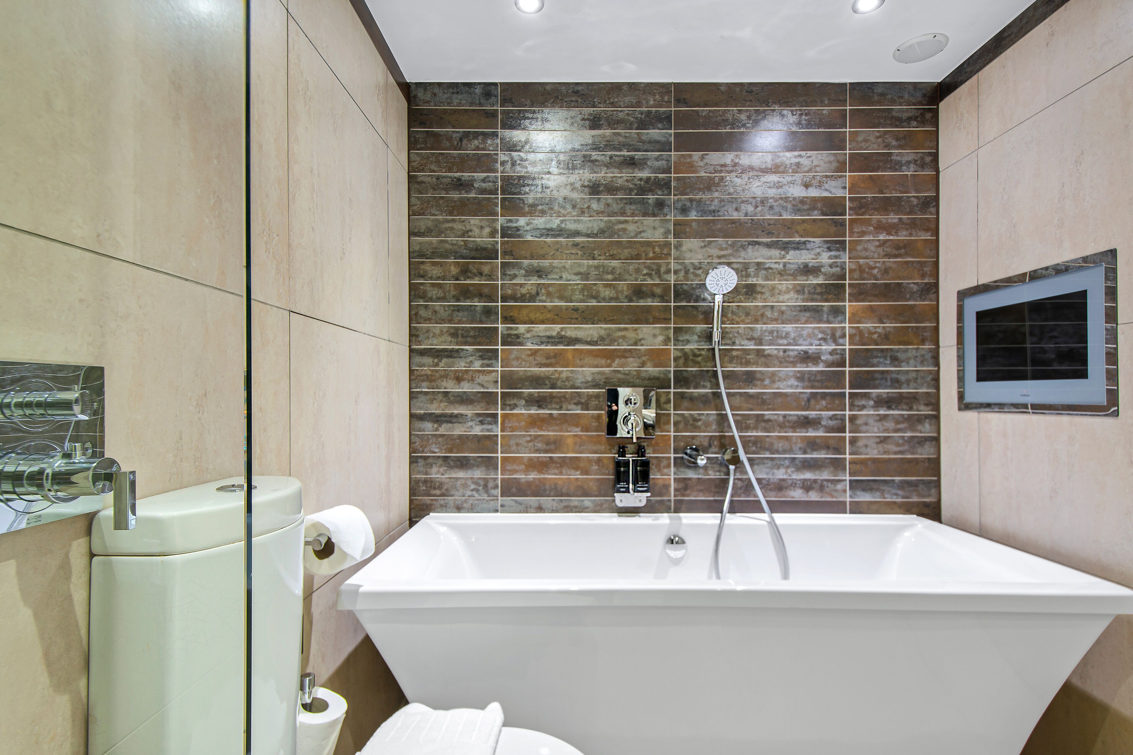 A modern bathroom with a freestanding bathtub, a toilet, and a glass shower enclosure.