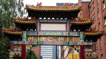 Um portão chinês tradicional com desenhos detalhados e uma placa com a inscrição 'China Town Manchester'.