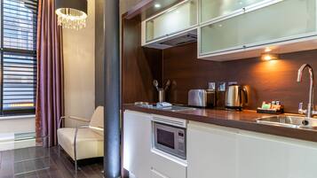 Cocina moderna con microondas integrado, pileta de acero inoxidable y un armario de vidrio sobre la encimera.