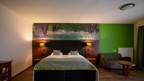 A hotel room with a large bed, a sofa, a small table, and a wall-mounted TV. - Boshotel Vlodrop (Vlodrop)