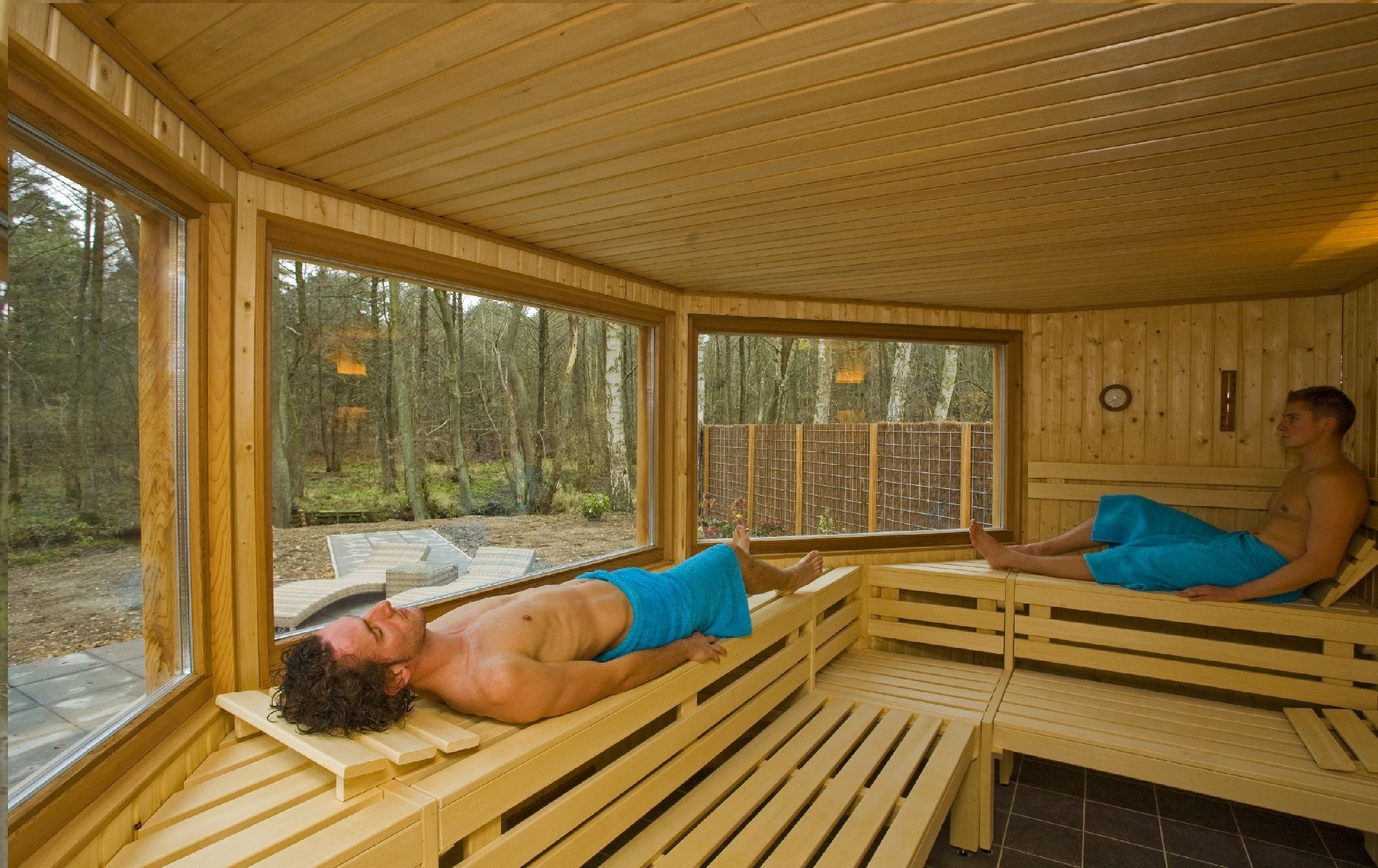 A sauna room with wooden benches and large windows.