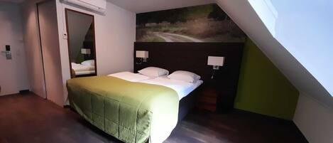 Una habitación de hotel con una cama, un cuadro en la pared y una puerta.