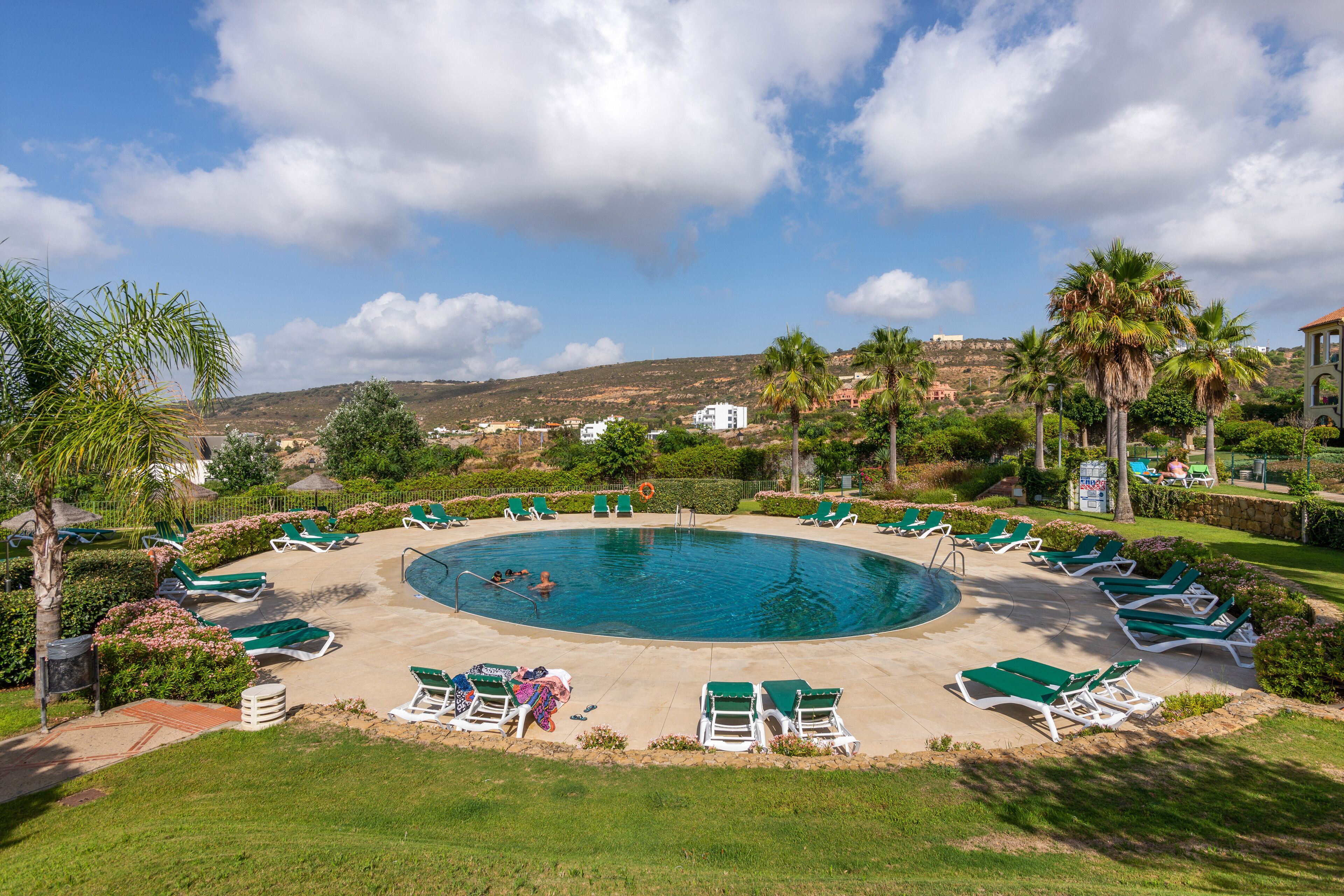 A pool area with sun loungers and a view of the surrounding landscape.