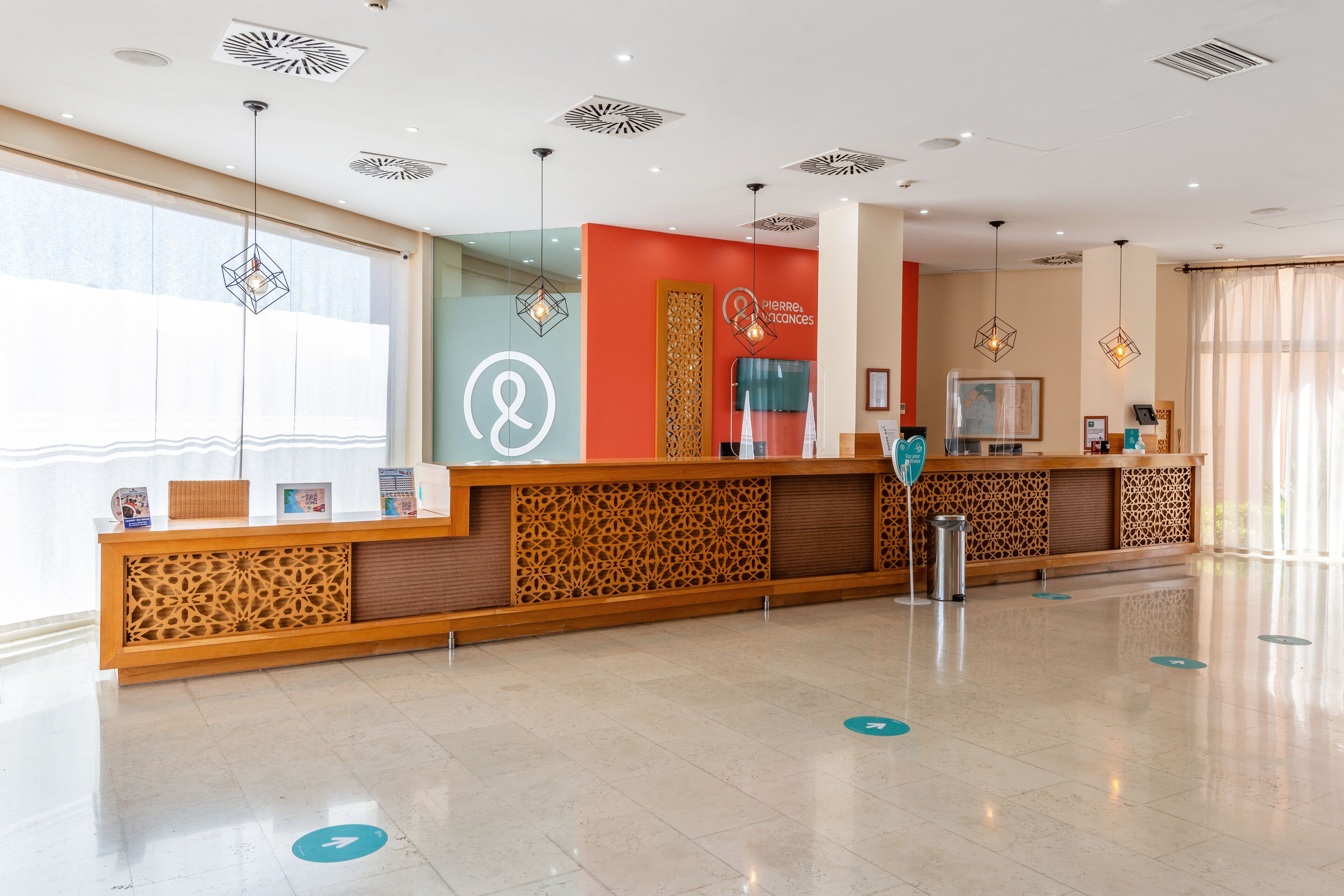 Een hotel receptie, modern ingericht, met een receptiebalie, decoratieve wandpanelen en hanglampen.