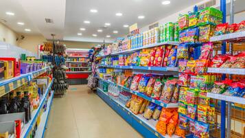 A supermarket aisle with shelves stocked with snacks, beverages, and household items.