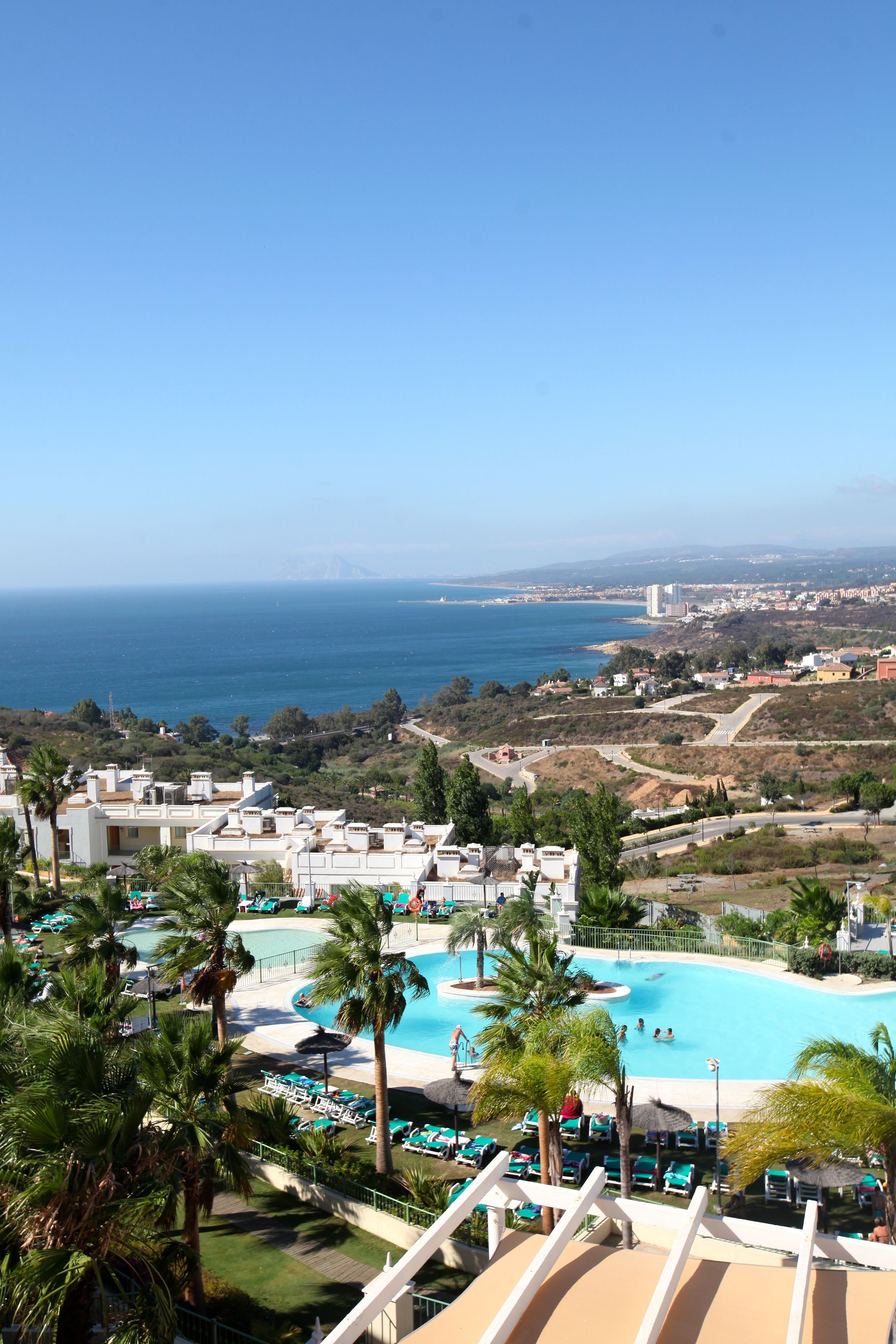 A resort with a swimming pool, palm trees, and a view of the ocean.