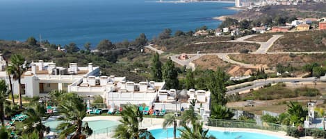 Un complex turístic amb piscina, palmeres i vista a l'oceà.