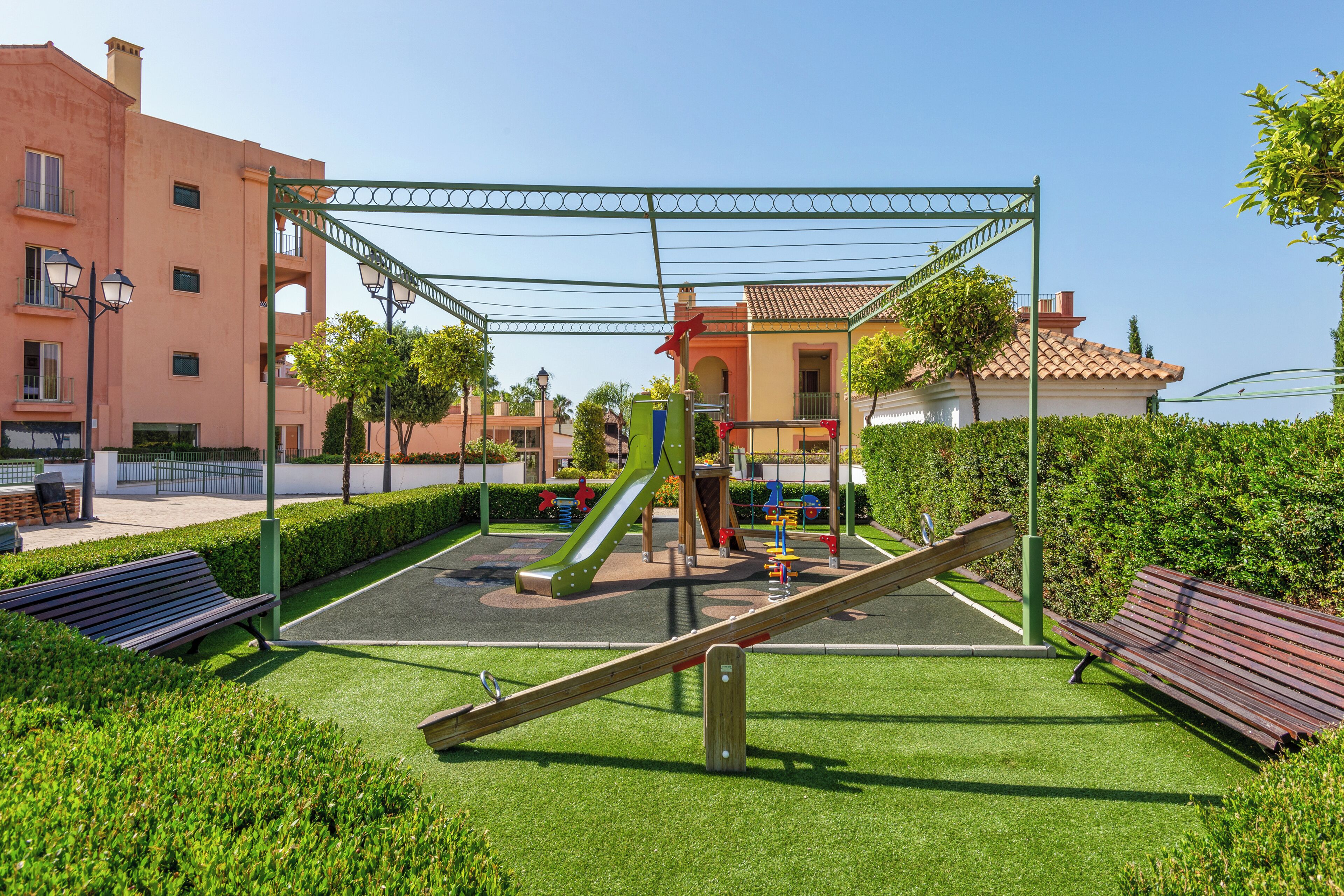 Une aire de jeux avec un toboggan, des balançoires et une bascule.
