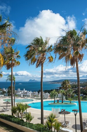 A resort with a large pool, palm trees, and a view of the sea. - Pierre & Vacances Resort Terrazas Costa del Sol (Manilva)