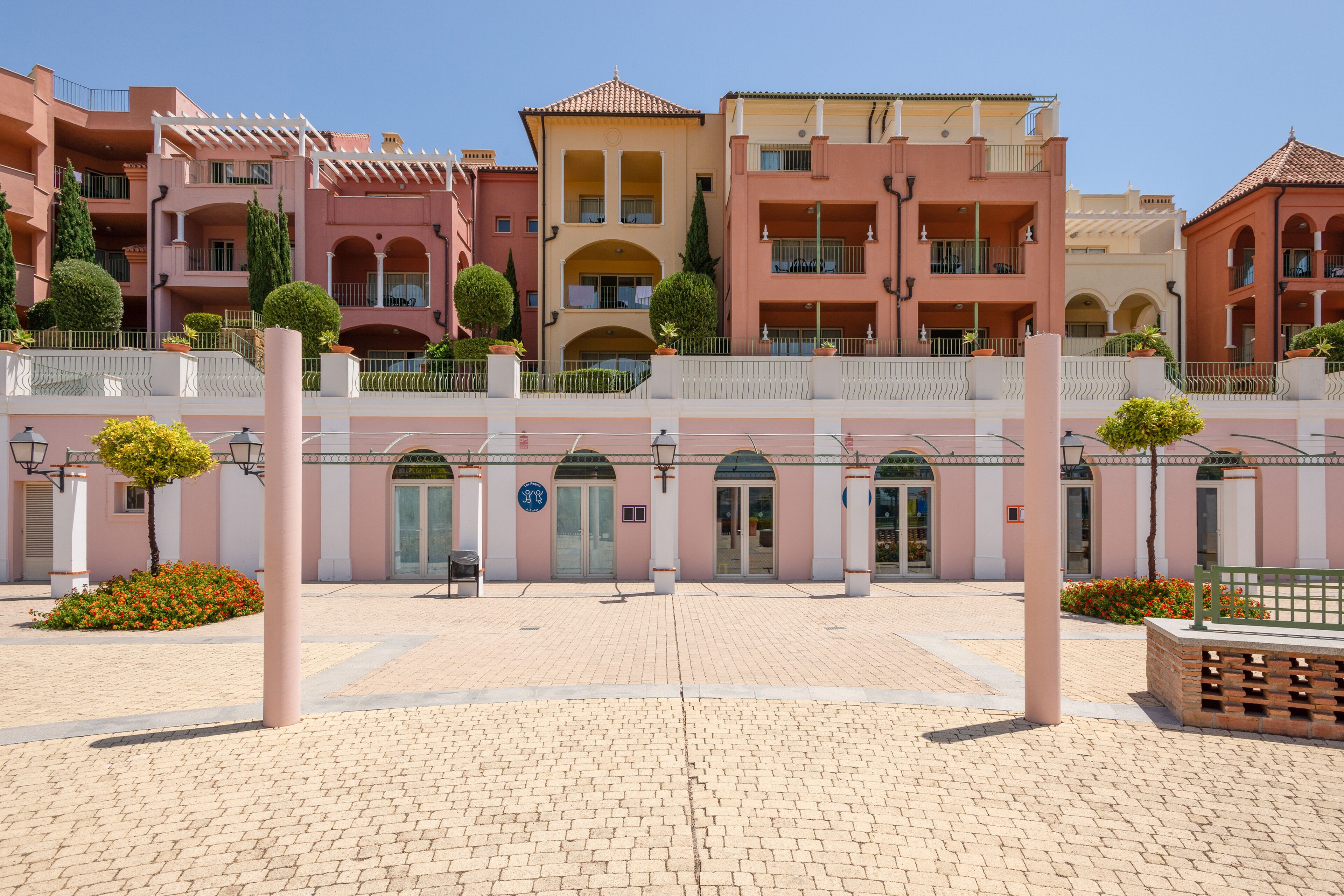 Un hotel de varios pisos con balcones, un patio central y piso de baldosas.