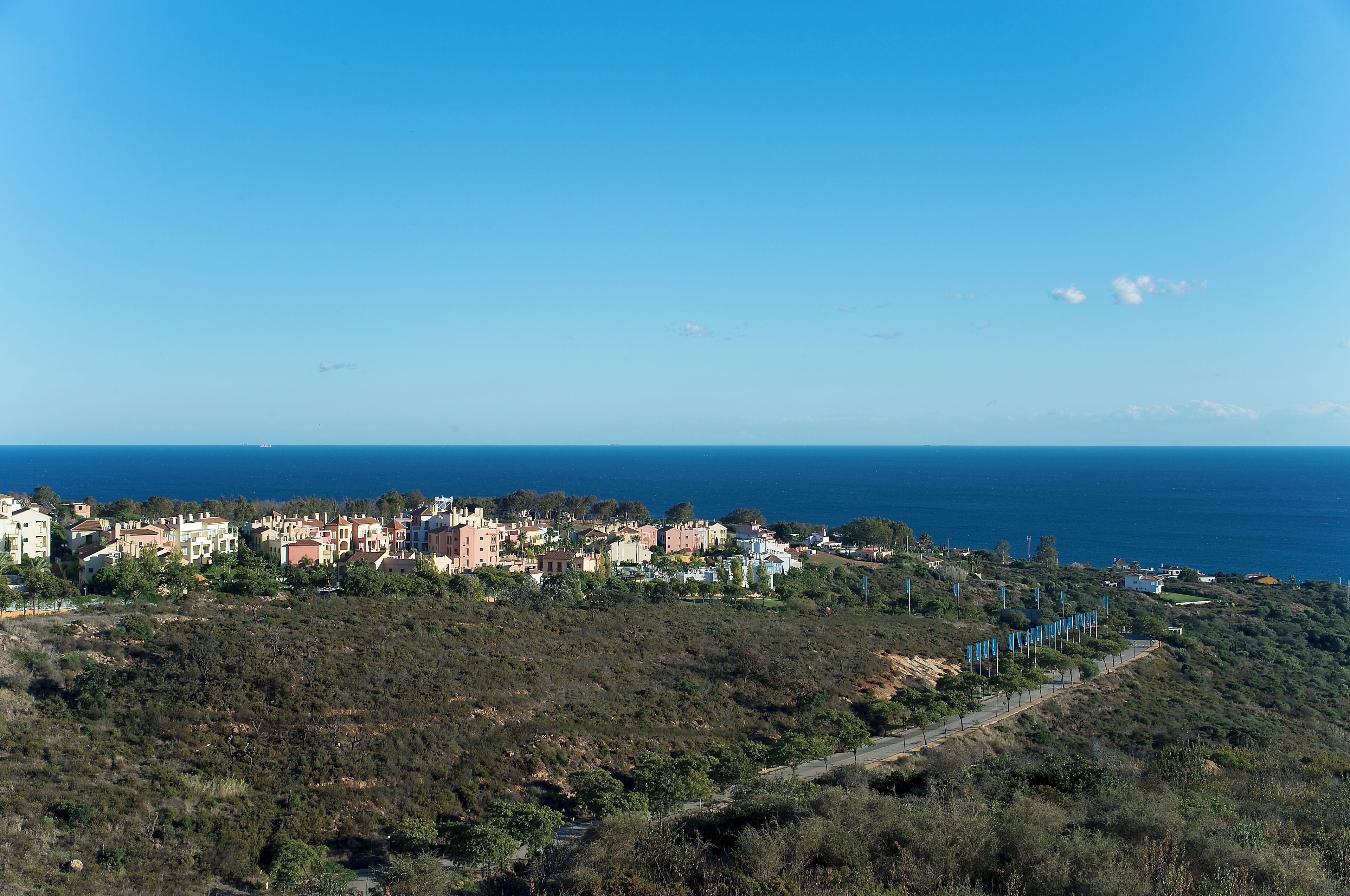A coastal town with buildings along the hillside and a clear view of the sea.