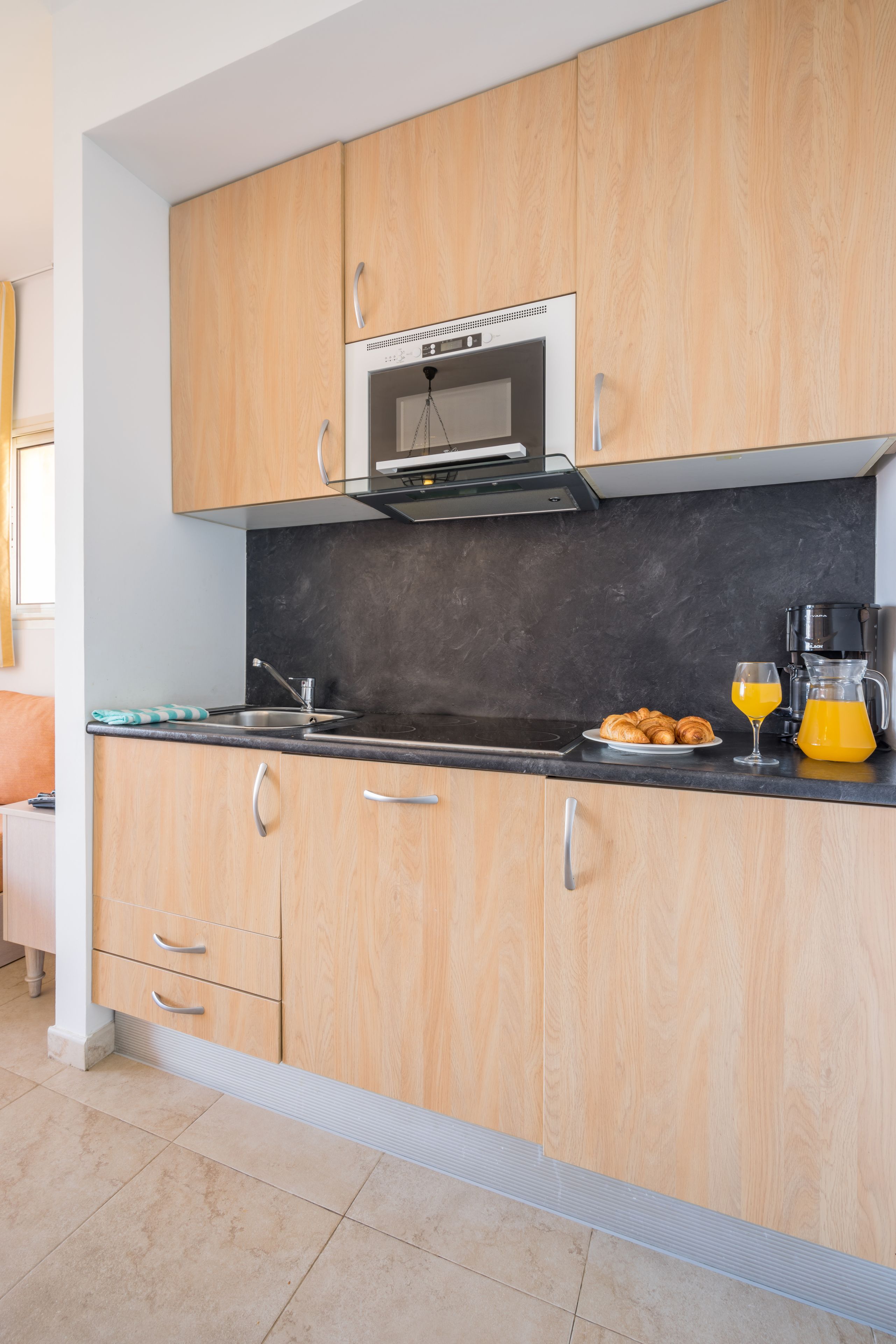 A kitchen with wooden cabinets, a stainless steel oven, a coffee maker, and a glass pitcher of orange juice.