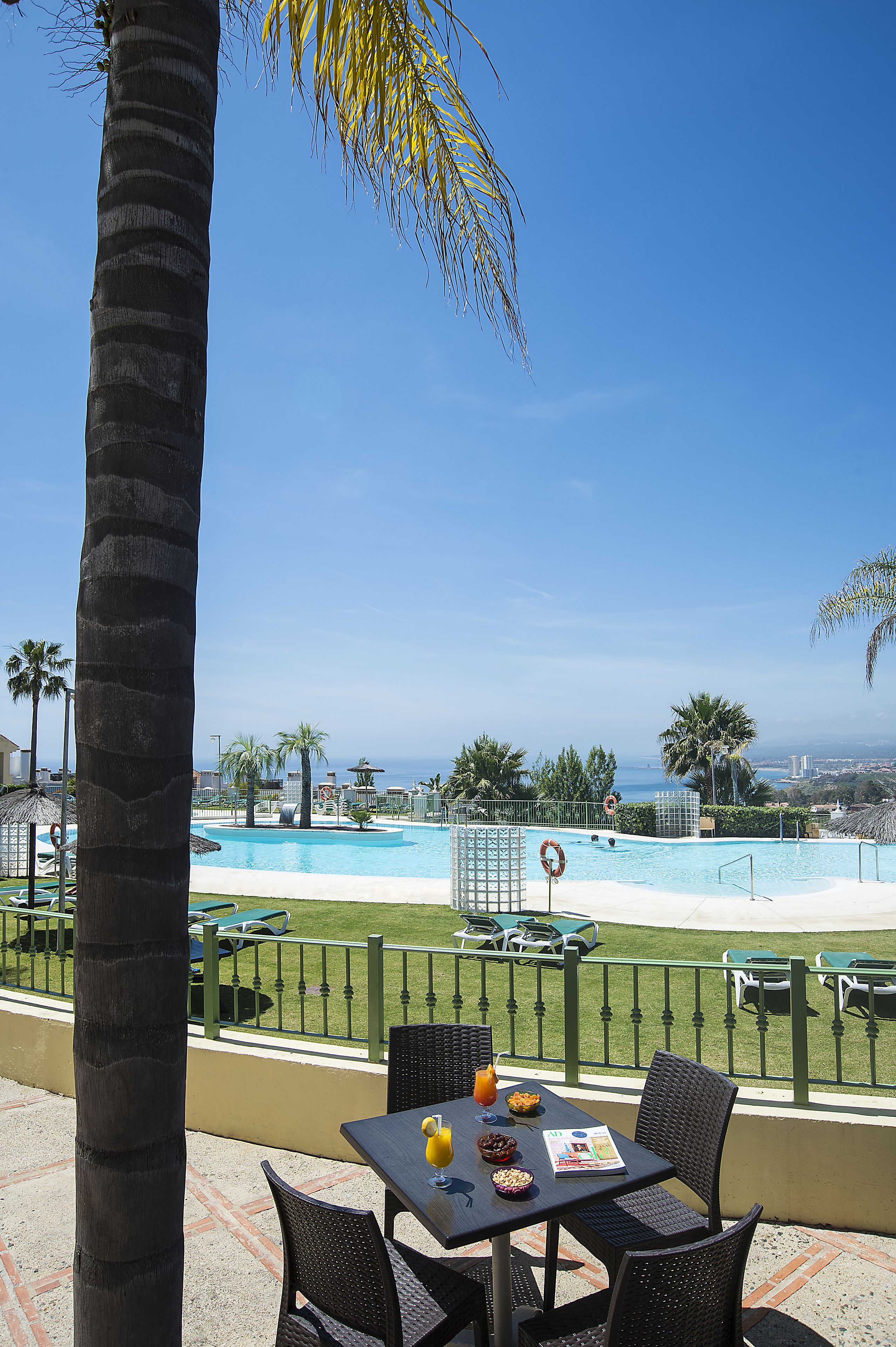 Zona junto a la piscina con mesa y sillas, un flotador salvavidas y vista al océano.