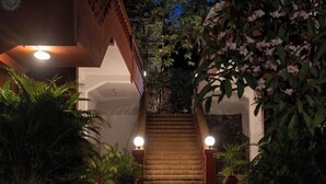 A staircase leading to a building entrance, surrounded by lush greenery and potted plants. - Pride Sun Village Resort & Spa (Arpora)