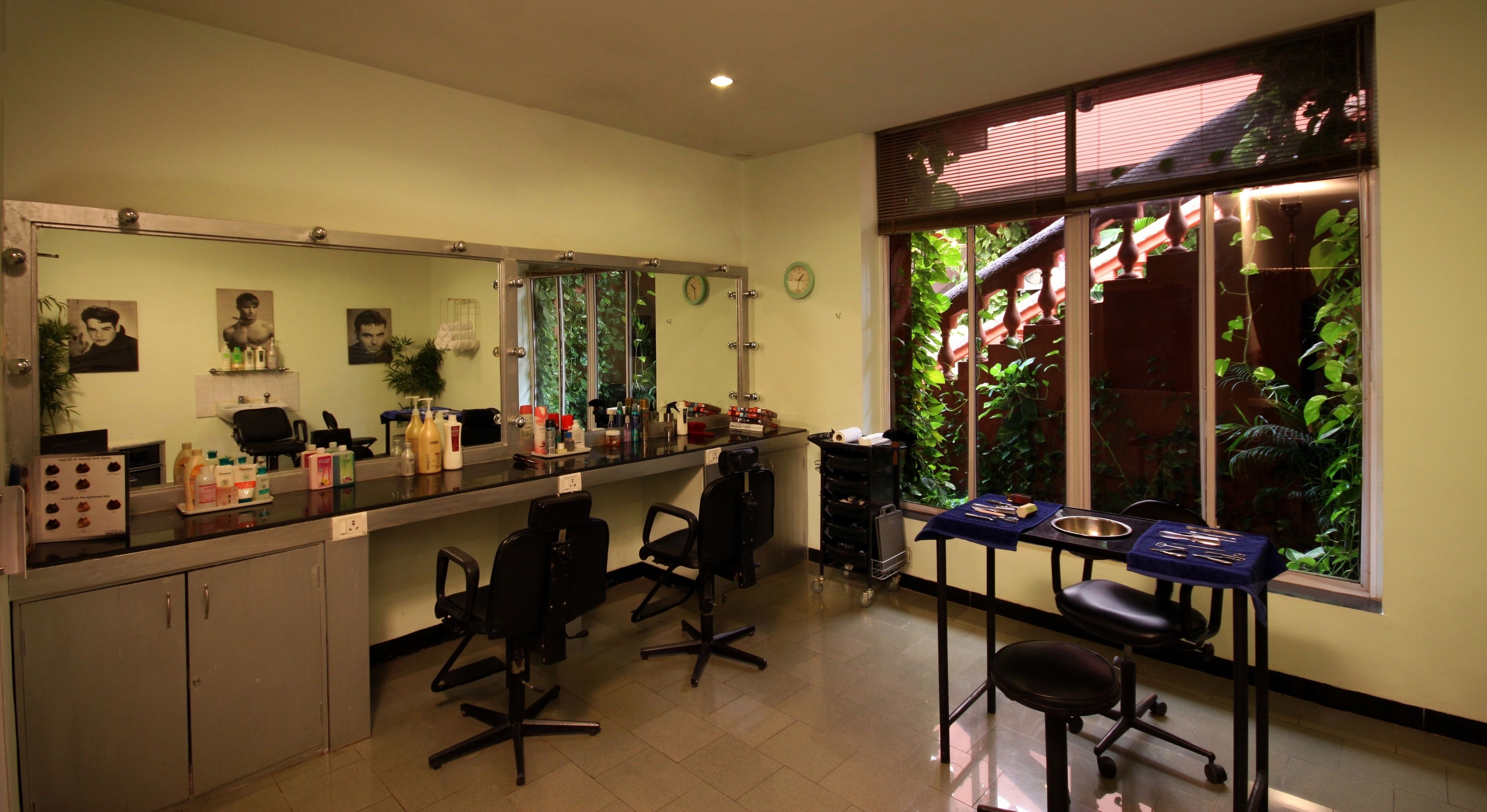 A salon with a large mirror, chairs, and various beauty products on the counter.