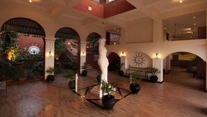 A spacious lobby with a high ceiling, arched doorways, and a central statue. - Pride Sun Village Resort & Spa (Arpora)