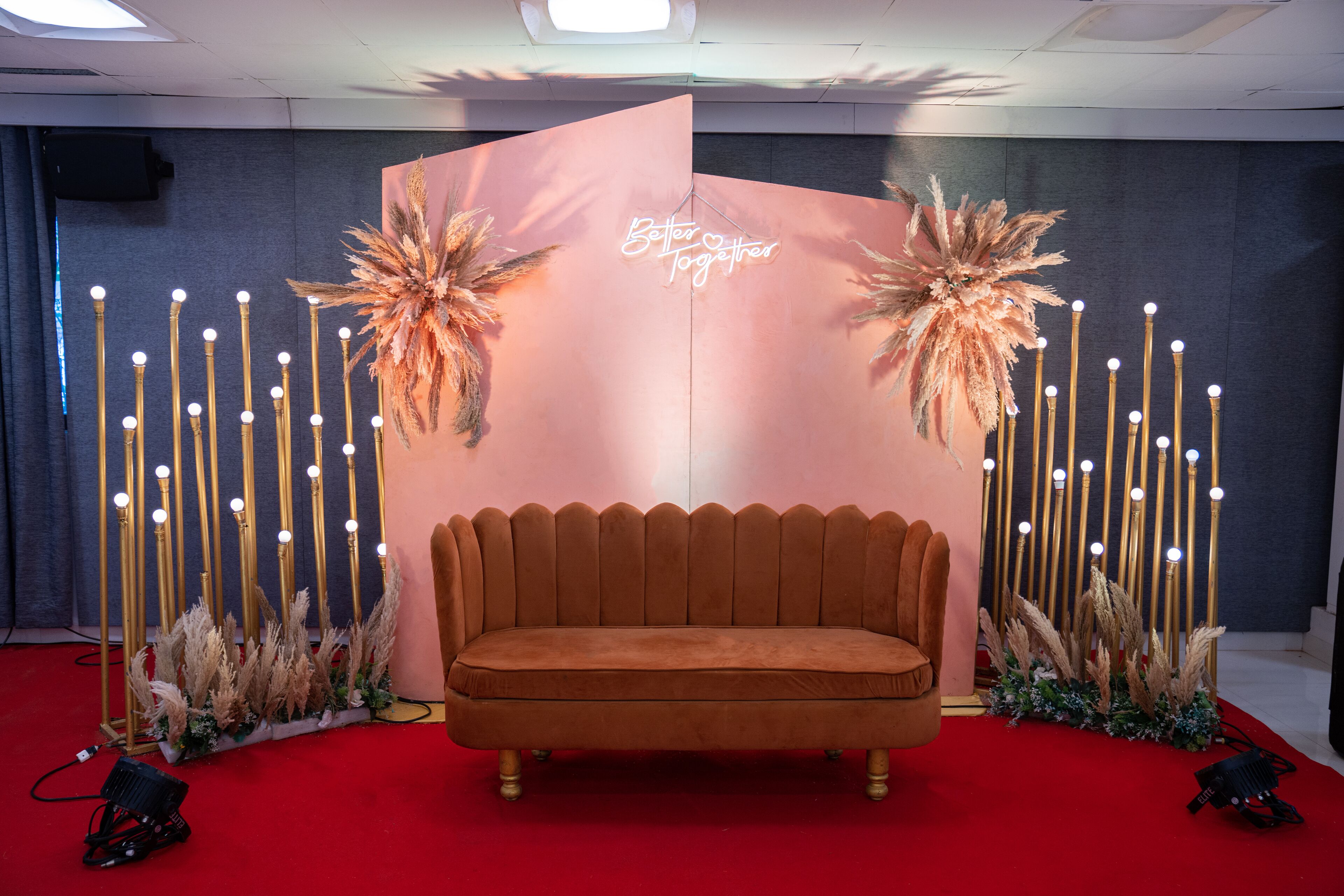 A red carpeted area with a velvet sofa, decorative plants, and a backdrop with the text "Better Together."