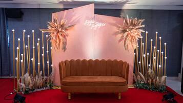 A red carpeted area with a velvet sofa, decorative plants, and a backdrop with the text "Better Together."