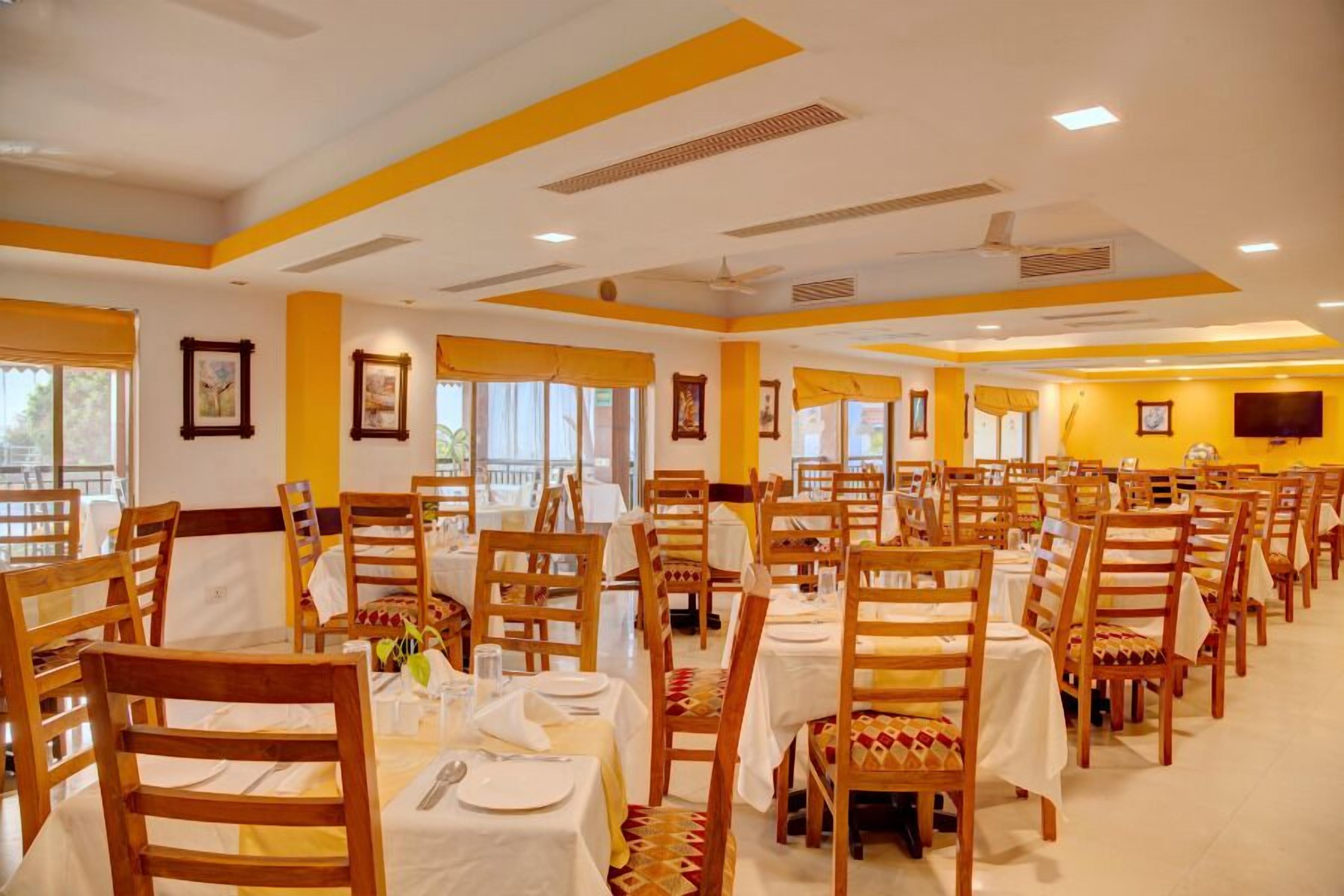 A dining area with multiple tables and chairs, arranged in rows, with a ceiling fan and recessed lighting.