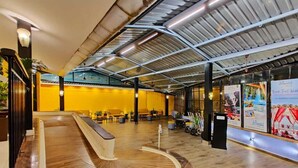 A spacious lobby with a curved reception desk, a high ceiling with exposed beams, and a seating area with chairs and tables. - Regenta Baywatch Resort Goa (Colva)